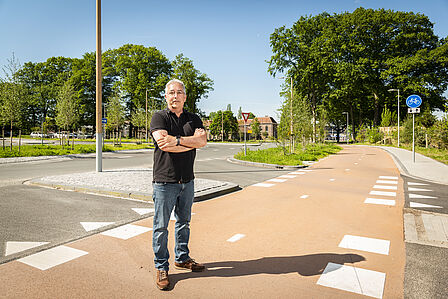 Adviseur Carlo van Rijswijk staat op een fietspad bij de Parklaan met op de achtergrond een bloeiende berm en groene bomen